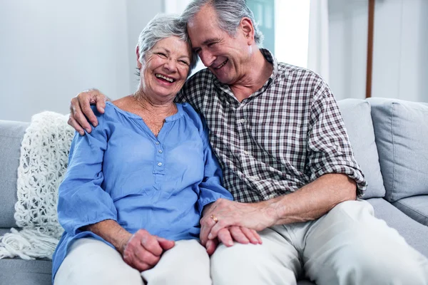 Feliz pareja de ancianos sentados en el sofá y abrazando —  Fotos de Stock