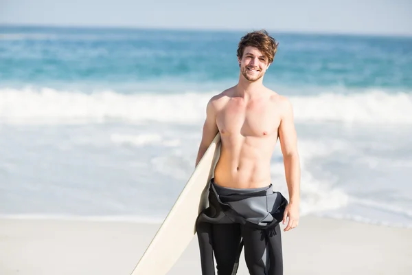 Hombre feliz sosteniendo una tabla de surf en la playa —  Fotos de Stock