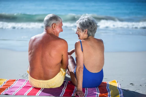 Söt äldre par sitter på en handduk på stranden — Stockfoto