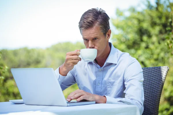 Kahve ile dizüstü bilgisayar kullanarak iş adamı — Stok fotoğraf