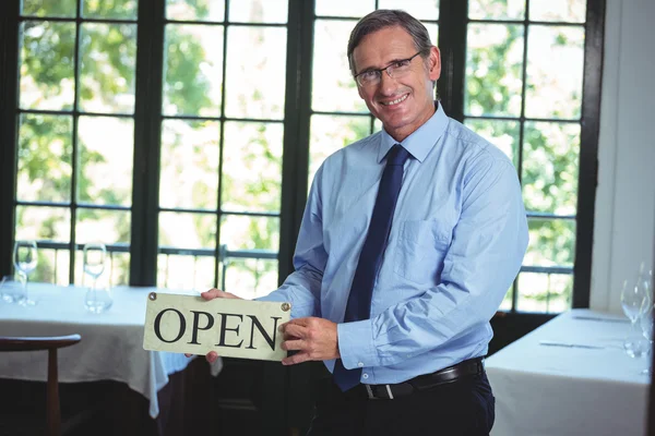 Un hombre de negocios sonriente sosteniendo un cartel abierto — Foto de Stock