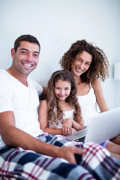 Retrato de pareja usando laptop con su hija en la cama —  Fotos de Stock