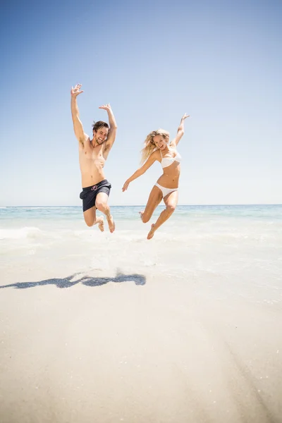 Casal feliz pulando na praia — Fotografia de Stock