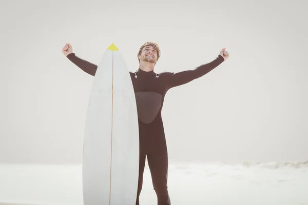 Homem feliz com prancha de surf em pé na praia — Fotografia de Stock