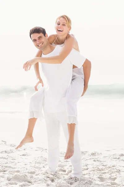 Muž dává prasátko zpět k ženě na pláži — Stock fotografie