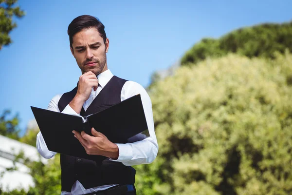 Gutaussehender Kellner beim Blick auf die Speisekarte — Stockfoto