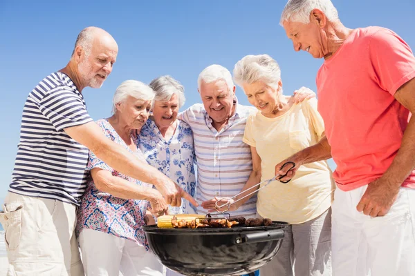 Amigos seniores fazendo um churrasco — Fotografia de Stock