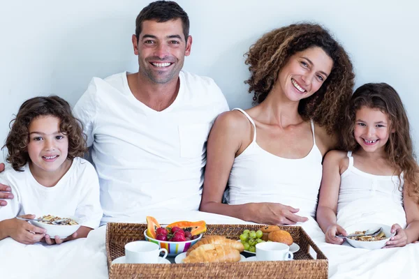 Famiglia seduta con vassoio per la colazione a letto — Foto Stock