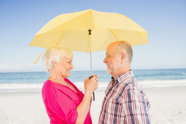 Souriant couple âgé tenant parapluie — Photo