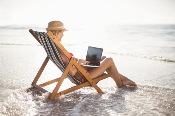 Kobieta siedzi na fotelu i za pomocą laptopa — Zdjęcie stockowe