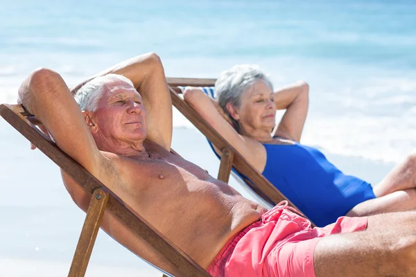 Söt äldre par ligga på solstolar — Stockfoto
