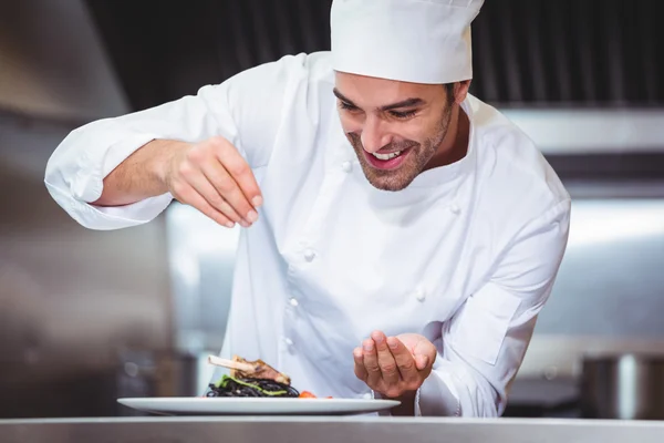 Chef sprinkling spices on dish — Stock Photo, Image