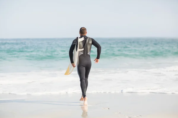 Surfista caminhando em direção ao mar com uma prancha — Fotografia de Stock