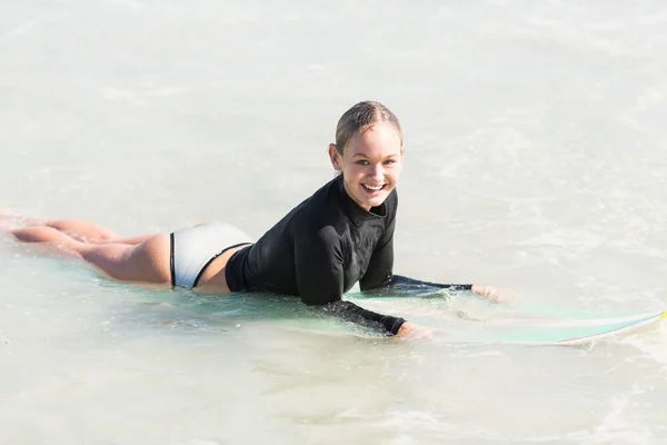 Glückliche Frau auf Surfbrett liegend — Stockfoto