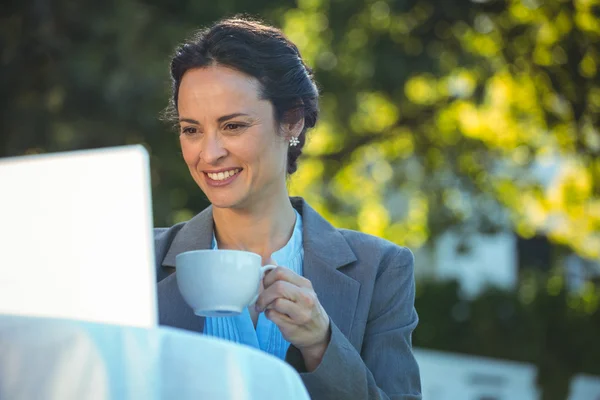 Empresária usando laptop com café — Fotografia de Stock