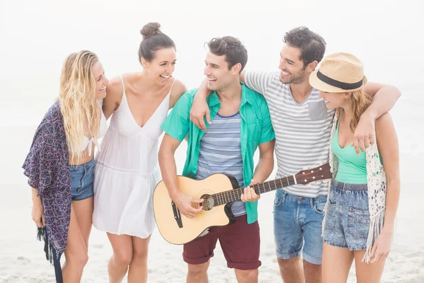 Grupo de amigos de pé na praia com uma guitarra — Fotografia de Stock