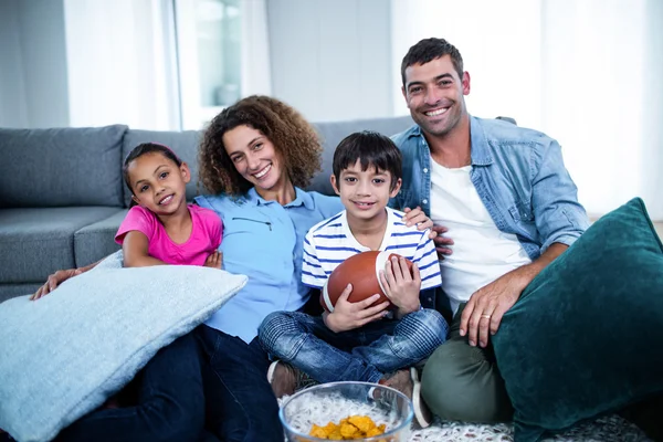 Porträtt av familj titta på amerikansk fotbollsmatch på televisio — Stockfoto