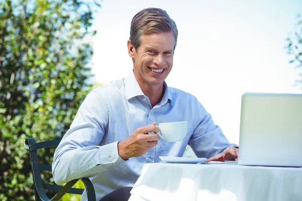 Casual businessman having coffee and using laptop — Stock Photo, Image