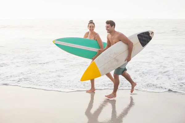 Coppia con tavola da surf corsa in spiaggia — Foto Stock