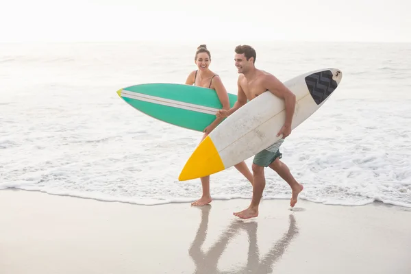 Casal com prancha de surf correndo na praia — Fotografia de Stock