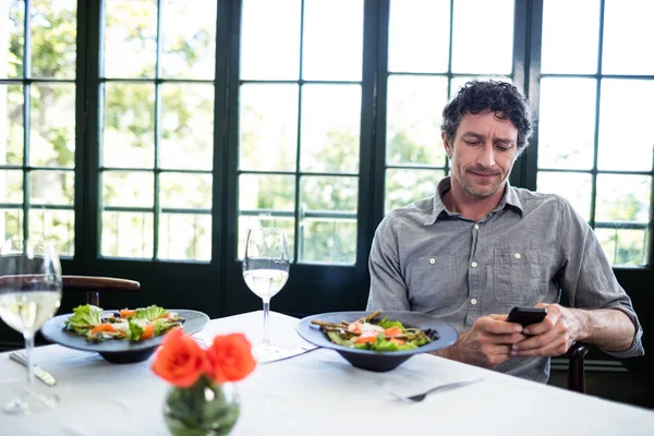 Человек в ресторане с помощью мобильного телефона — стоковое фото