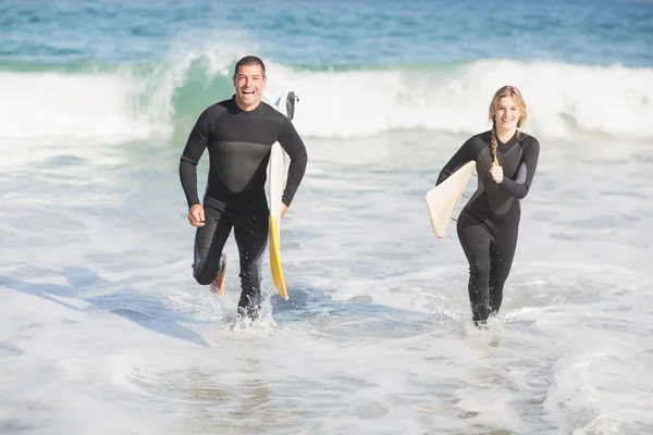 Casal com prancha de surf correndo na praia — Fotografia de Stock