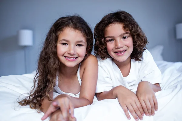 Irmão e irmã deitados na cama — Fotografia de Stock