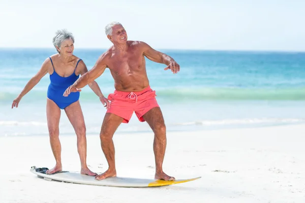 Söt äldre par stående på en surfbräda — Stockfoto