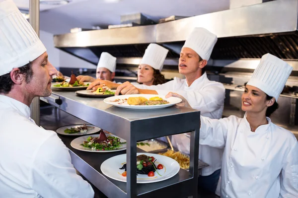 Chefs handing dinner plates — Stock Photo, Image