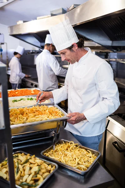 Chef-kok permanent bij het bakken van de pasta serveren — Stockfoto