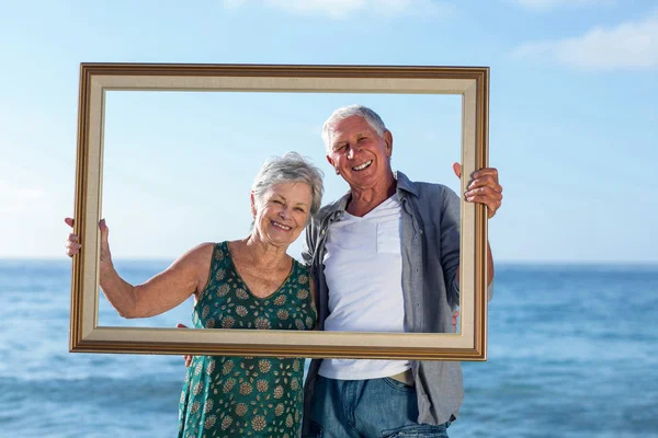 Senior paar posiert mit einem Rahmen — Stockfoto