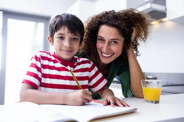 Felice madre aiutare il figlio con i compiti — Foto Stock