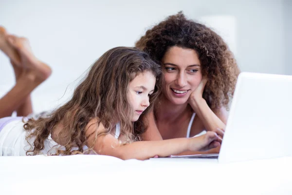 Madre e hija usando portátil en la cama — Foto de Stock