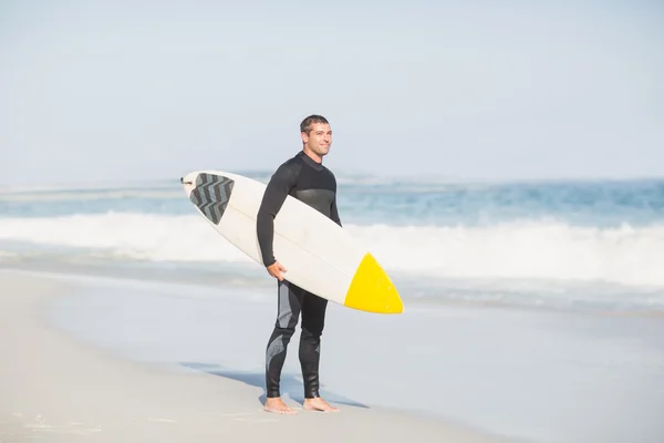 Серфер, держащий доску для серфинга на пляже — стоковое фото