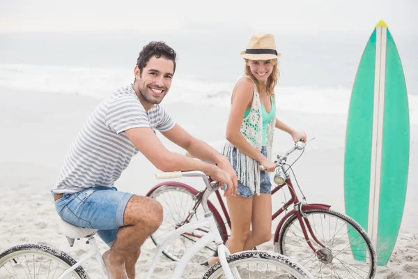 Lyckliga paret med sin cykel på stranden — Stockfoto