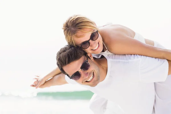 Homem dando um porquinho de volta para a mulher na praia — Fotografia de Stock