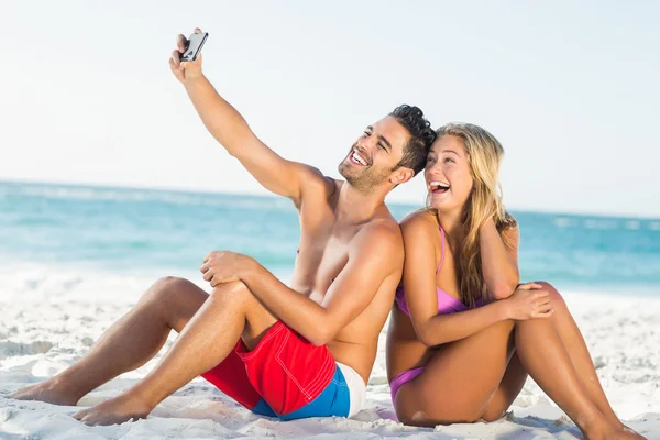 Lyckliga paret sitter rygg mot rygg på stranden — Stockfoto