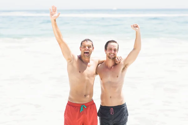 Dva muži stojící pláž s rukama nad hlavou — Stock fotografie