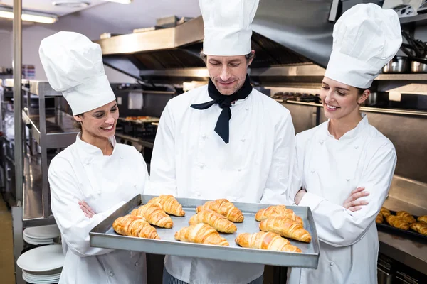 Cozinheiros segurando bandeja de croissants cozidos — Fotografia de Stock