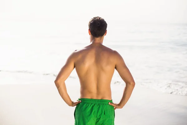 Homem em calções de banho em pé na praia — Fotografia de Stock