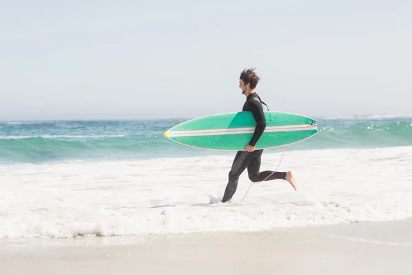 Man with surfboard running towards sea — Stock Photo, Image