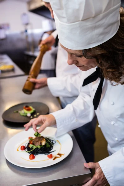 Chef garnishing meal on counter — Stock Photo, Image