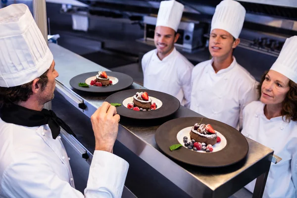 Chefe de cozinha inspecionando pratos de sobremesa — Fotografia de Stock