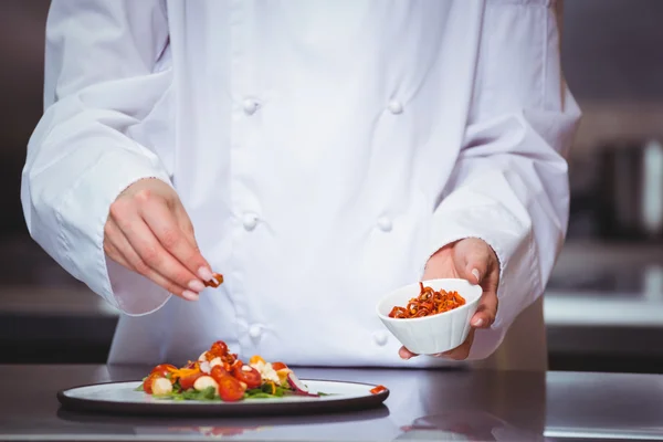 Chef sprinkling spices on dish — Stock Photo, Image