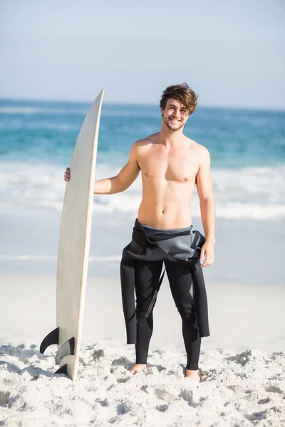 Hombre feliz sosteniendo una tabla de surf en la playa —  Fotos de Stock