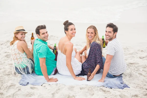 Vänner som sitter sida vid sida på stranden — Stockfoto