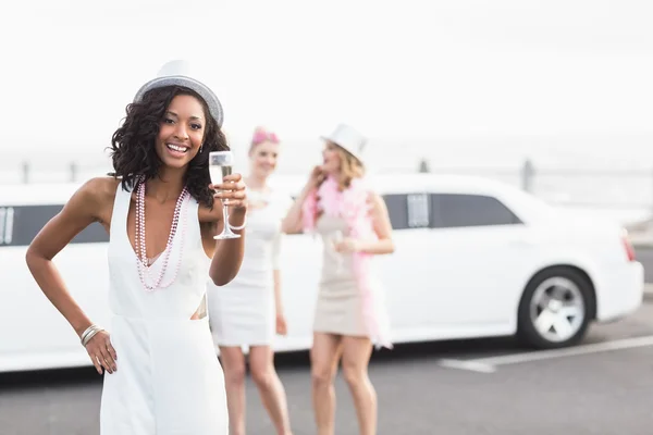 Frivolous women drinking champagne next to a limousine