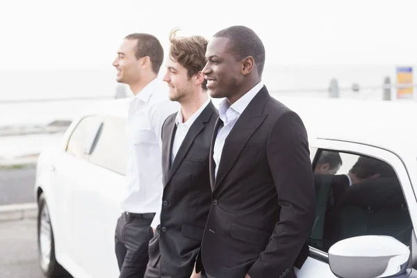 Välklädda män poserar lutande på en limousine — Stockfoto
