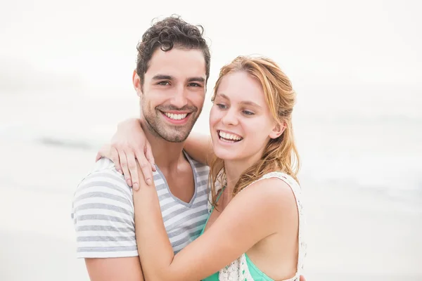 Ungt par omfamnar varandra på stranden — Stockfoto