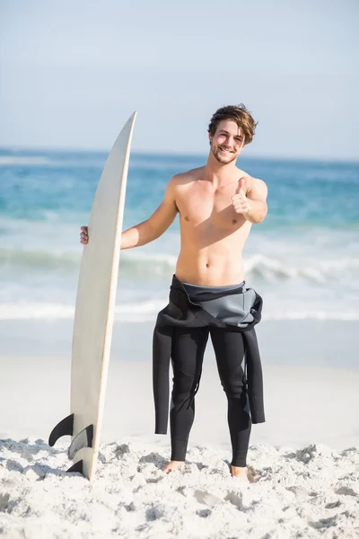 Man med surfbräda visar tummen på stranden — Stockfoto